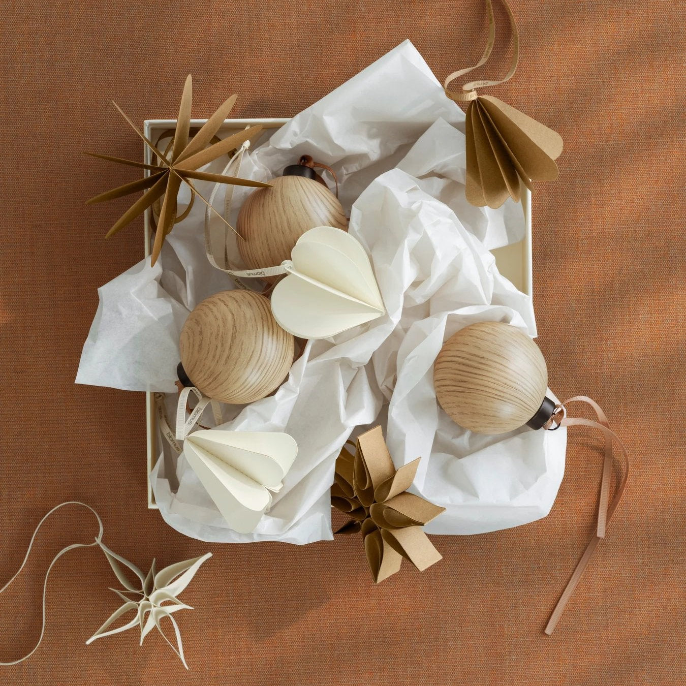 Decorative items including wooden balls and dried plants in a box on a brown textured surface