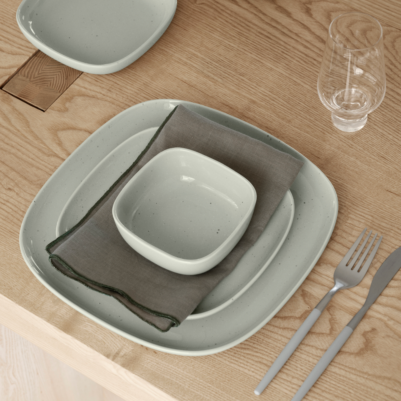 VAHLO Placesetting in Mirage Grey on a wood table with KOYOI Glass and silverware.