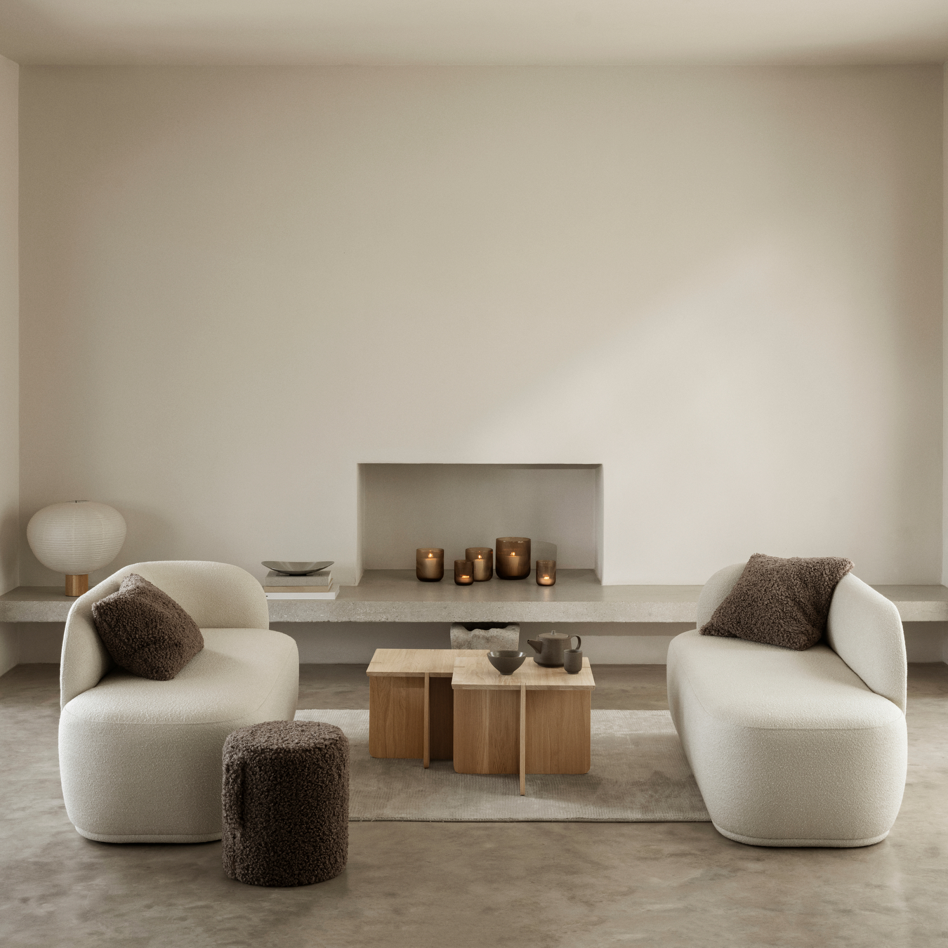 ENGAWA Tables in a living room setting in front of a modern fireplace containing VEN Candle Holders. Living room also contains couches and a TEDDY Pouf.