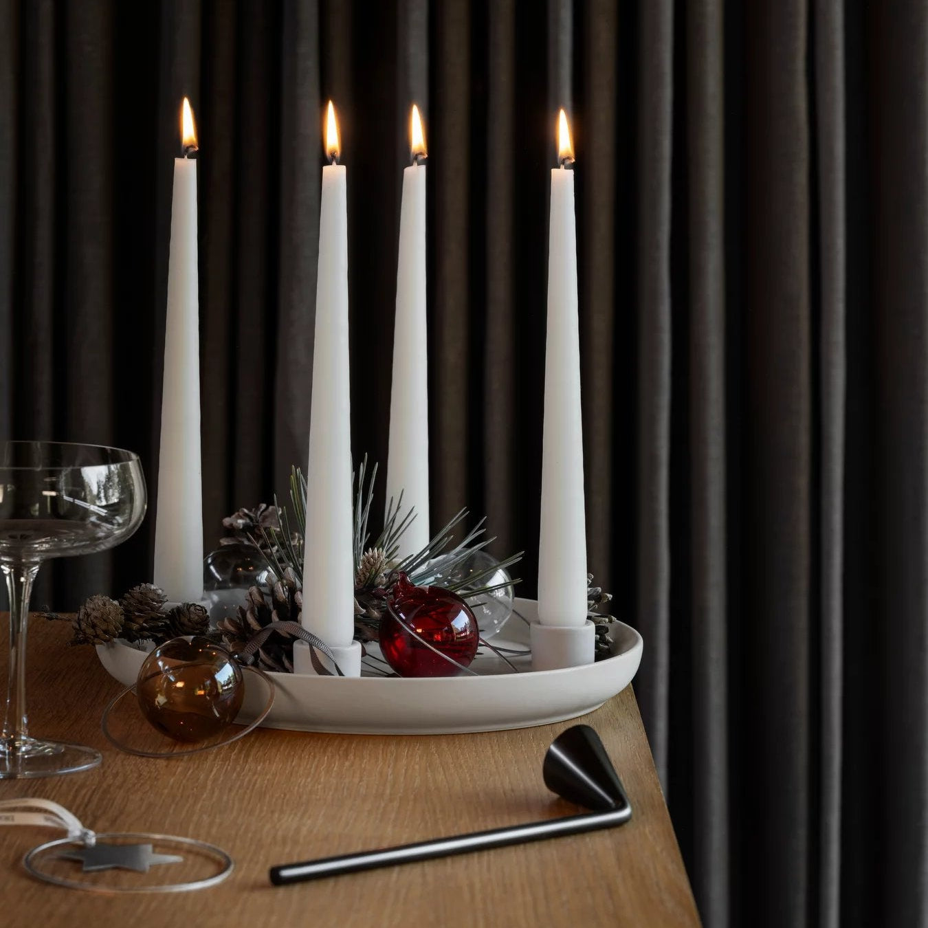 White candles on a decorative plate with a dark curtain background