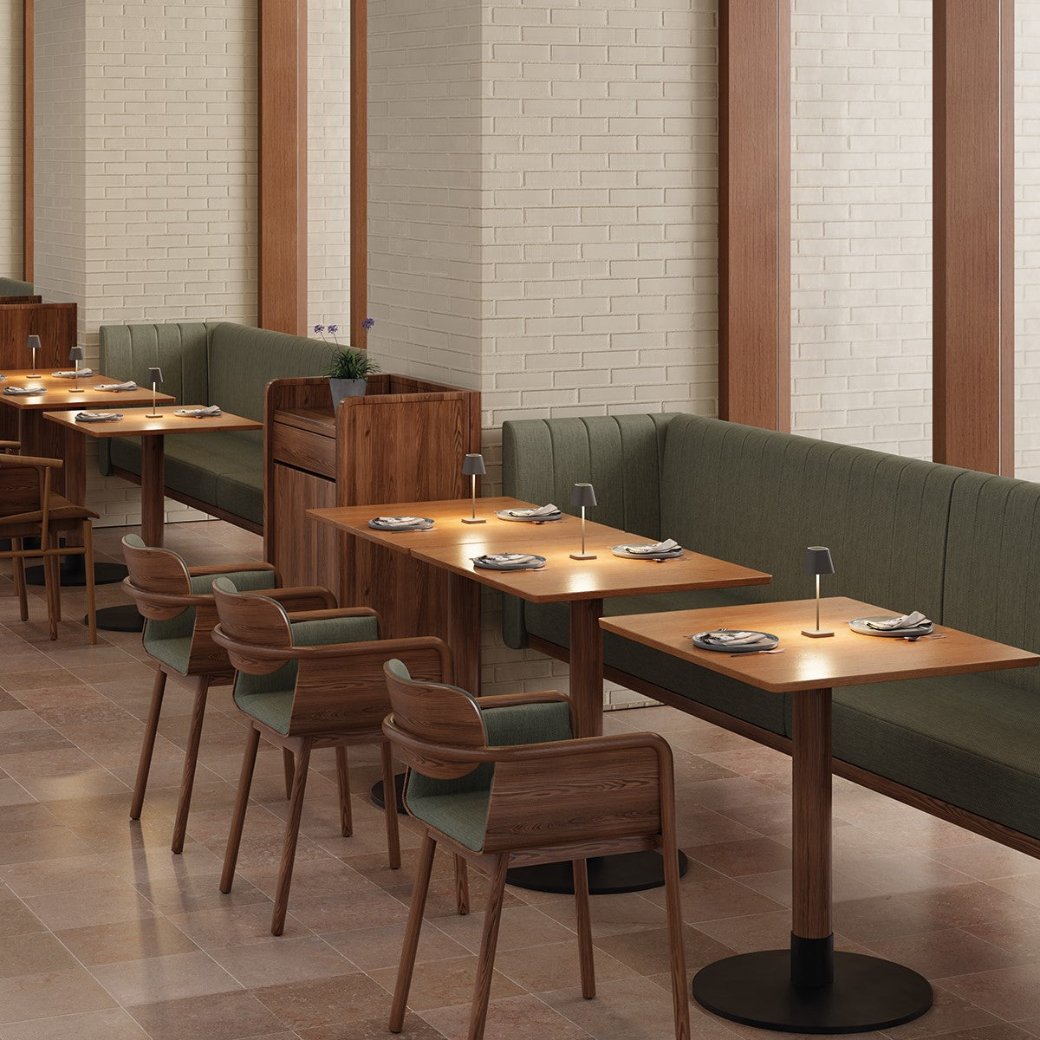Contemporary restaurant setting with wooden chairs and green fabric benches and light reflecting off wood tables from led lights
