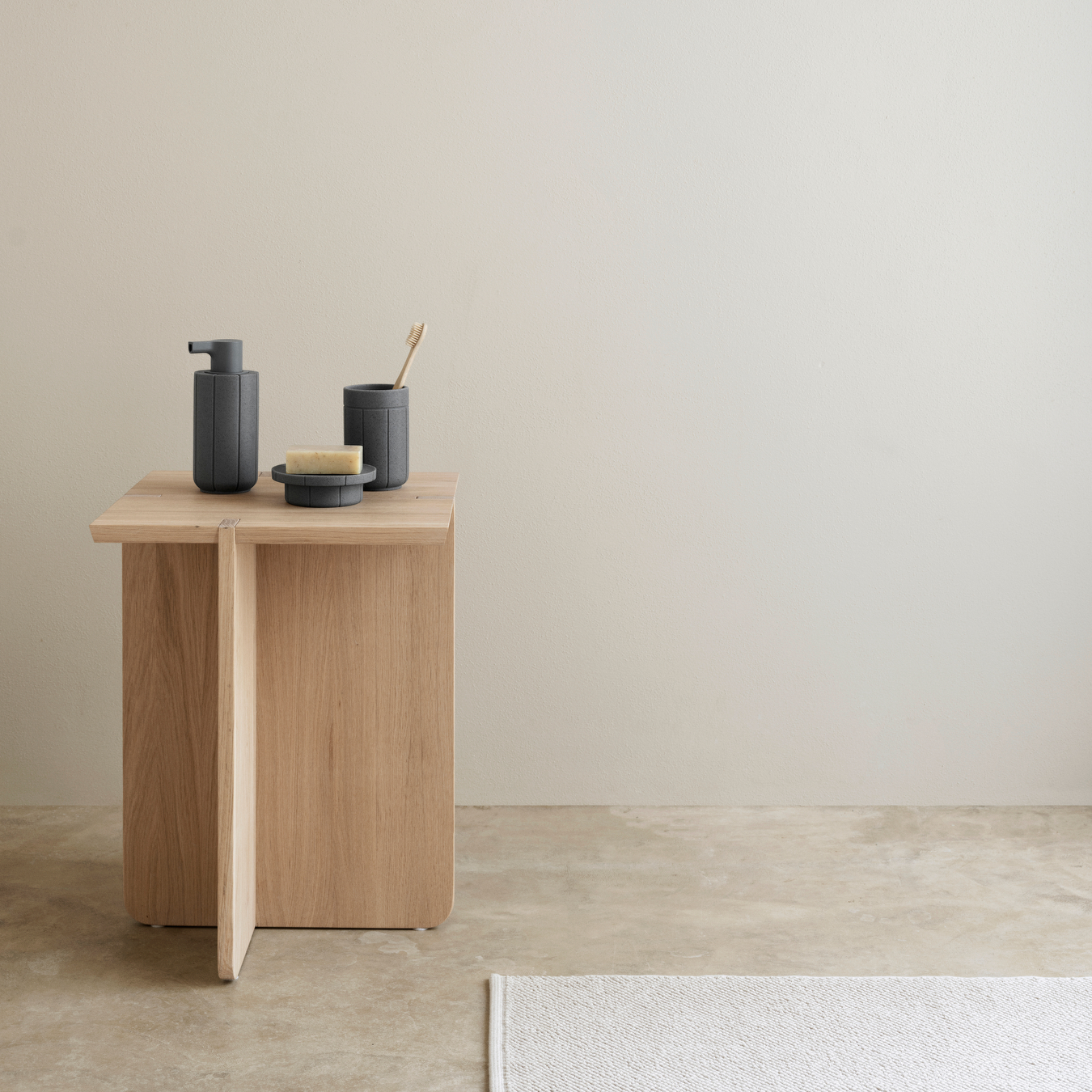 ENGAWA Stool with KUA Soap Dispenser, Tumbler and Tray sitting on top placed in a neutral colored room.