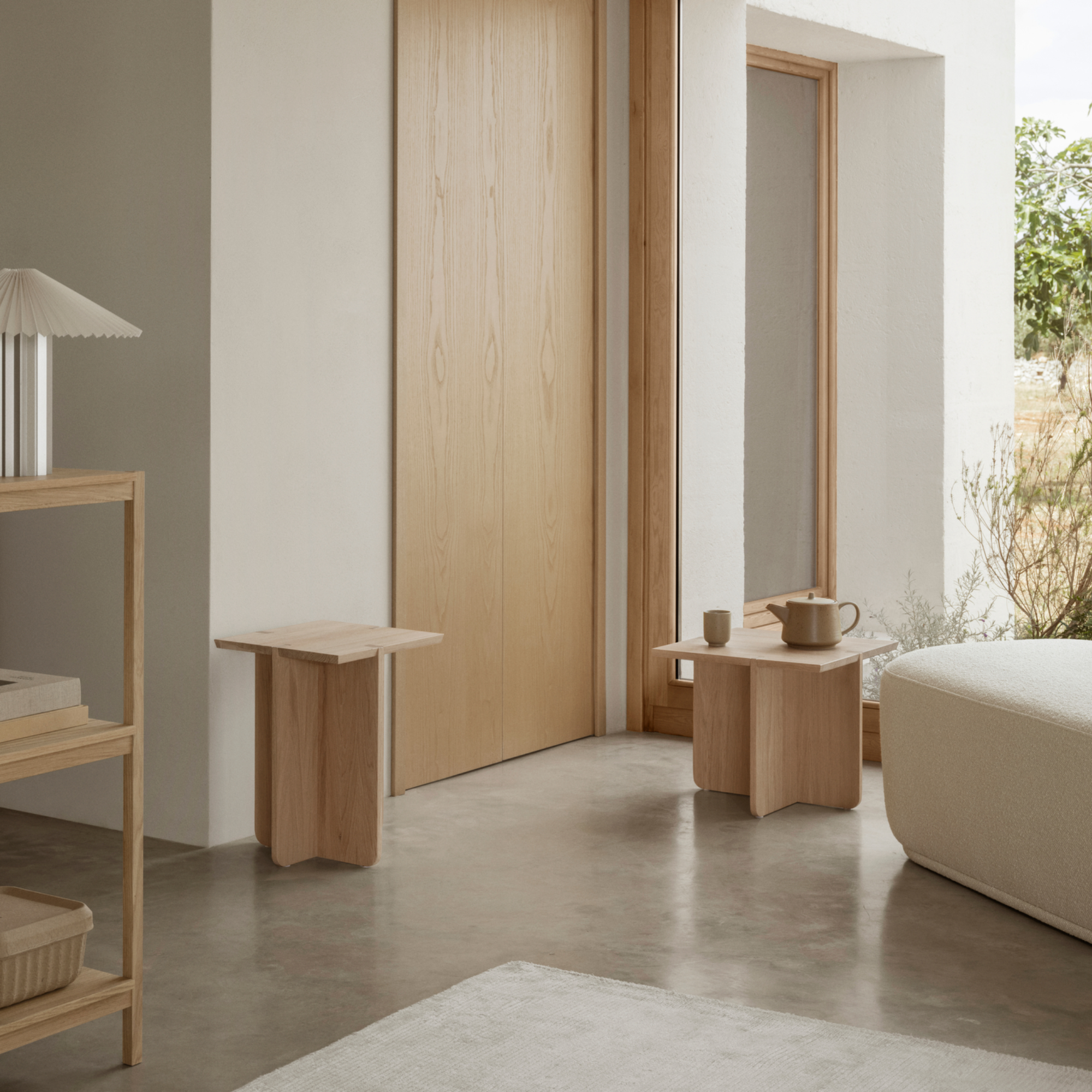 ENGAWA Stool and Side Table shown in a neutral room with other furnishings and a large window showing outdoor plants.