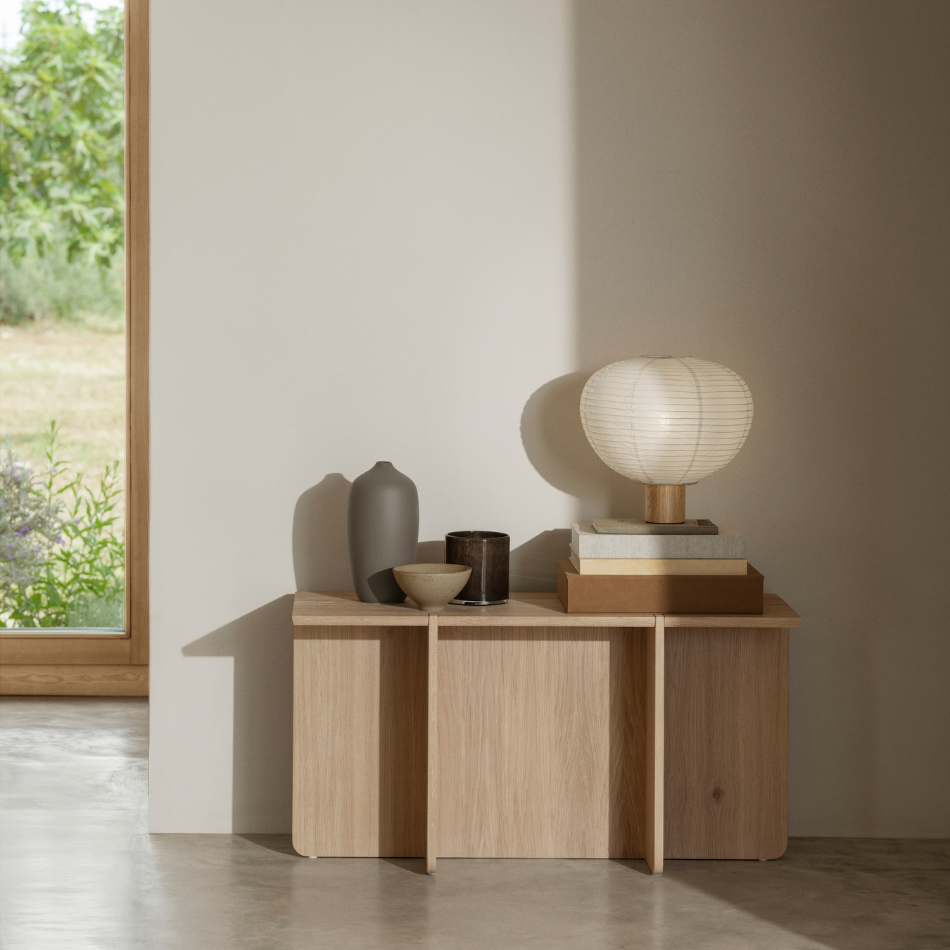 ENGAWA Oak Bench used as a table with vases, books and a lamp sitting on top in a neutral colored room.