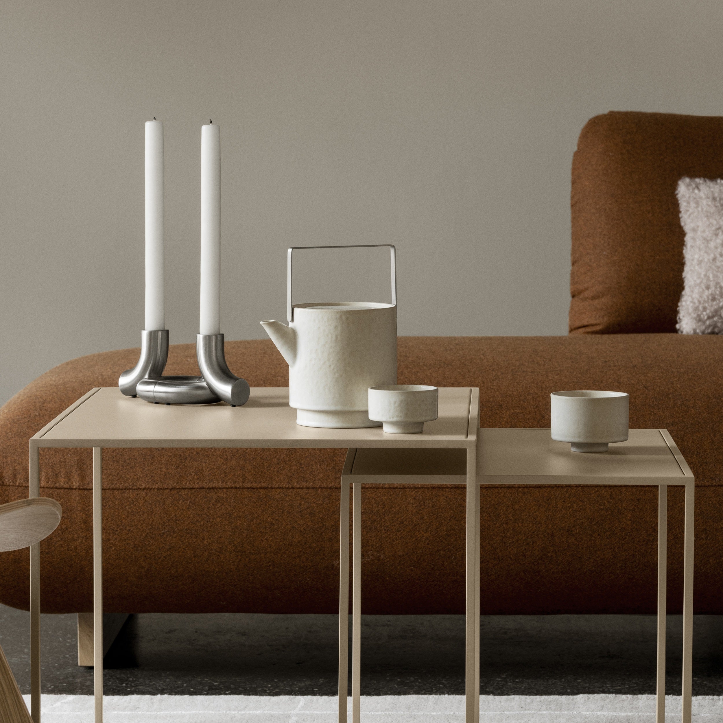 Modern living room with a sofa, side table, and decorative items including DOODLE Candle Holders.