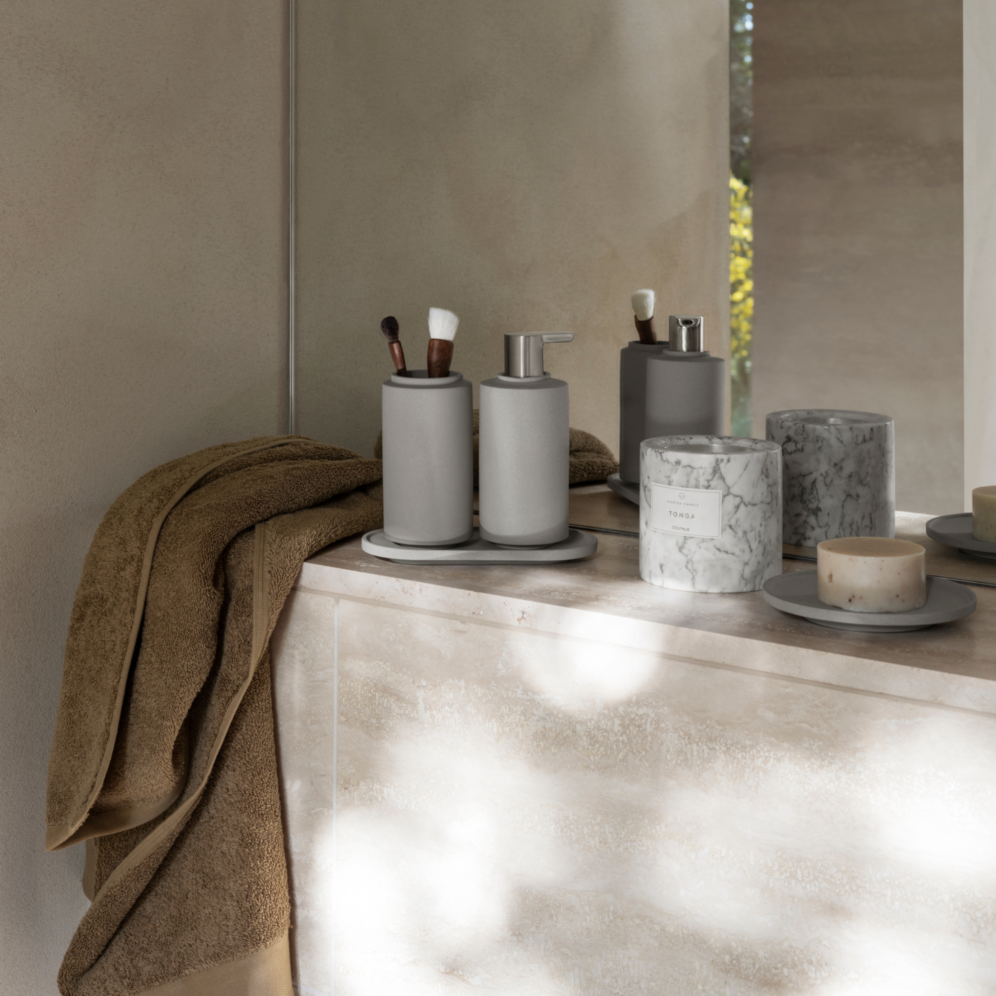 stone ledge in bathroom with bath accessories and soy based candle in a marble container