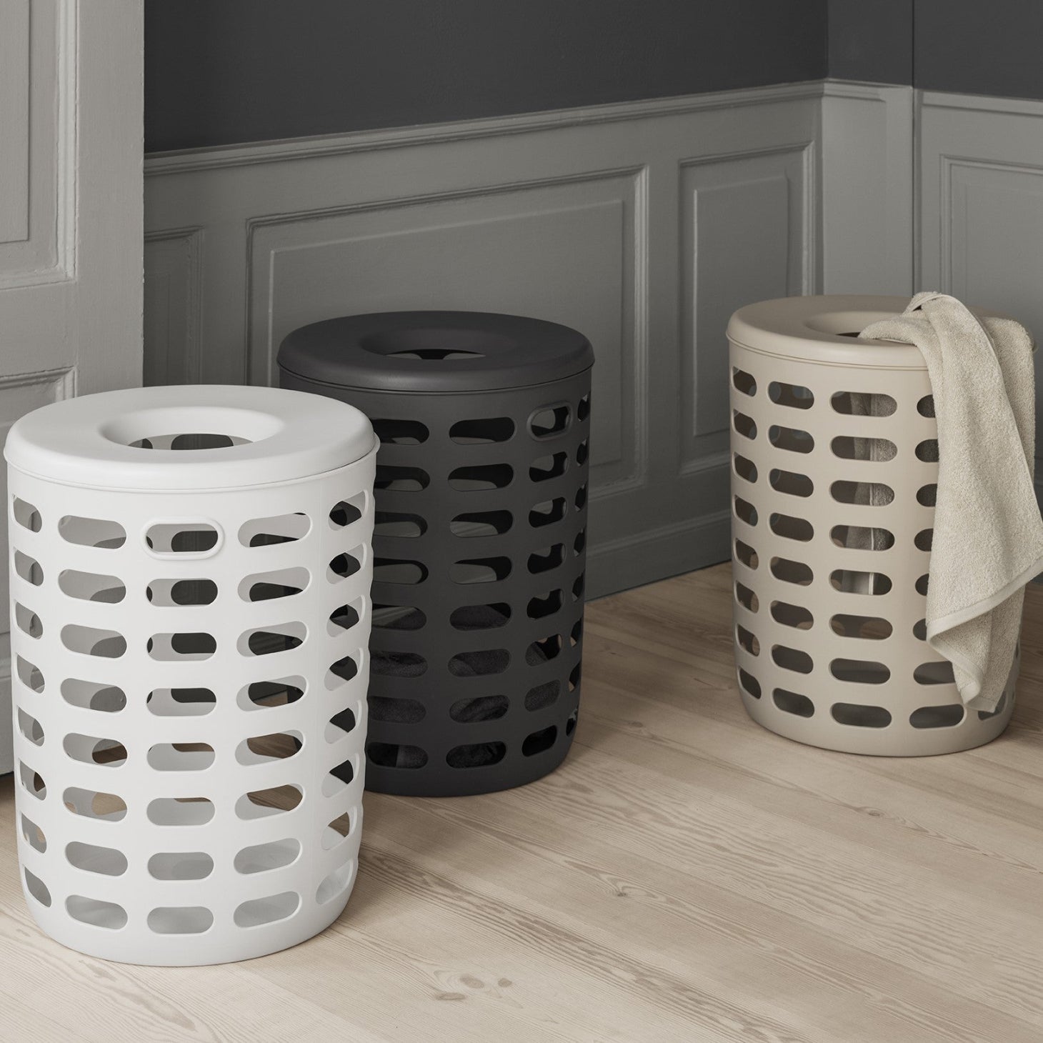 three colors of KORIE plastic laundry bin in a modern house with wood floors