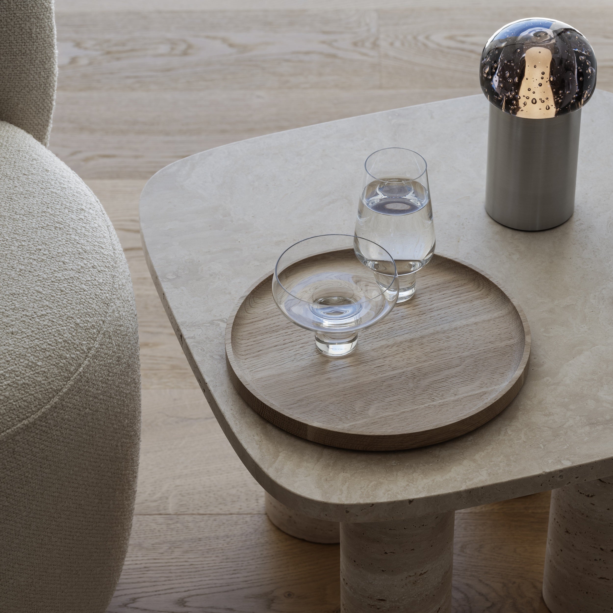water glasses presented on round oak tray with natural wood finish next to a chair