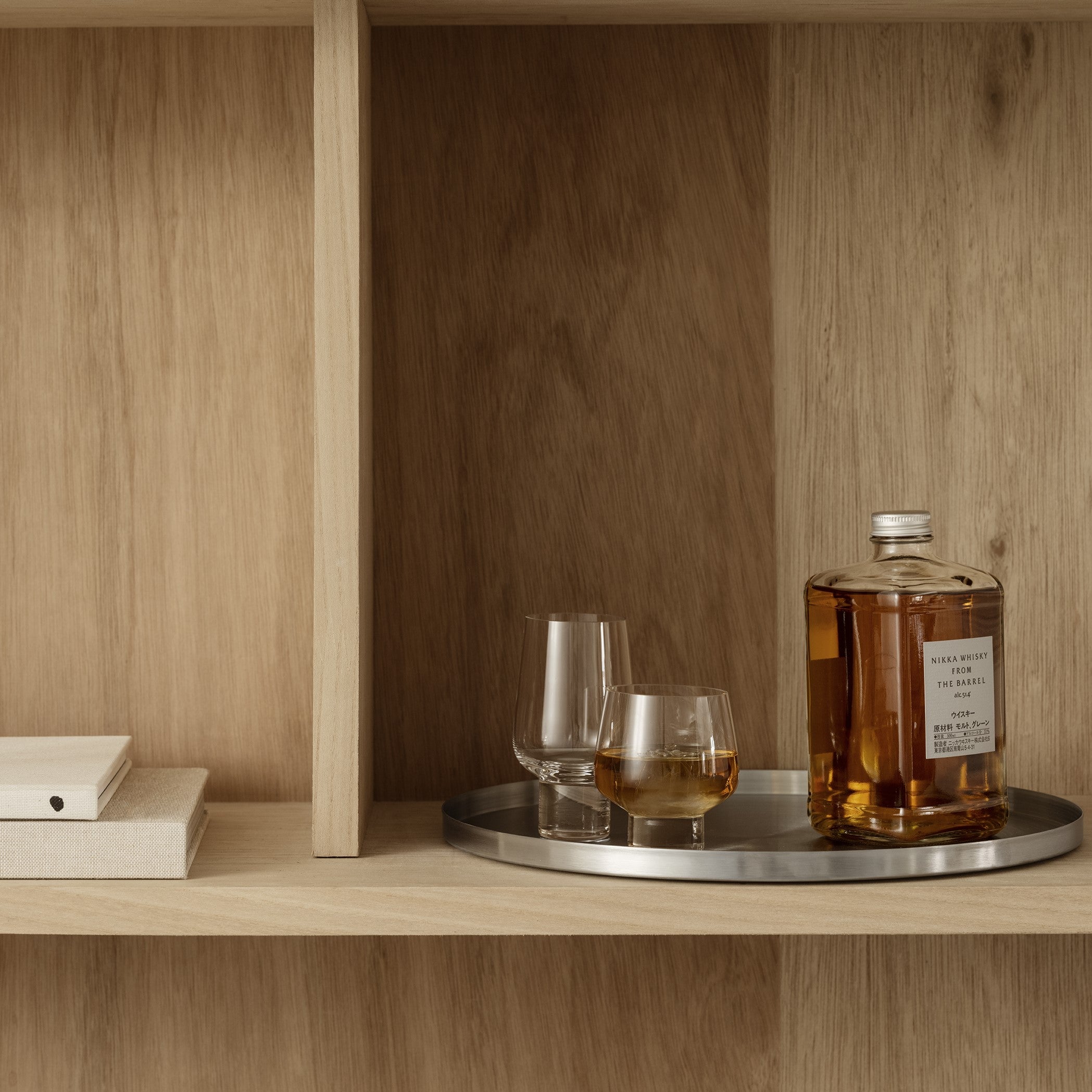 Modern Oak cabinet with round steel tray displaying blomus KOYOI whiskey glasses
