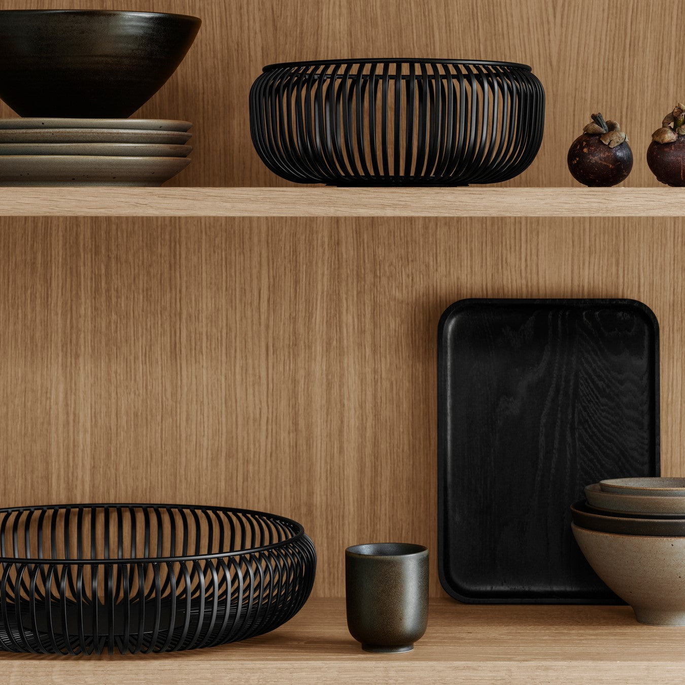 minimalist kitchen cabinets displaying dishes and black metal LITO bowls from blomus