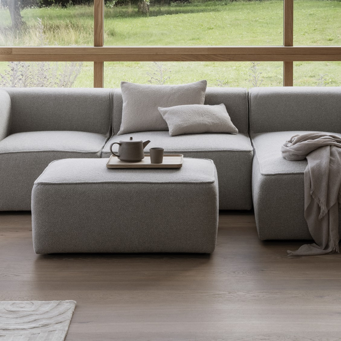 tea served on a rectangular natural oak tray by a cozy modern couch