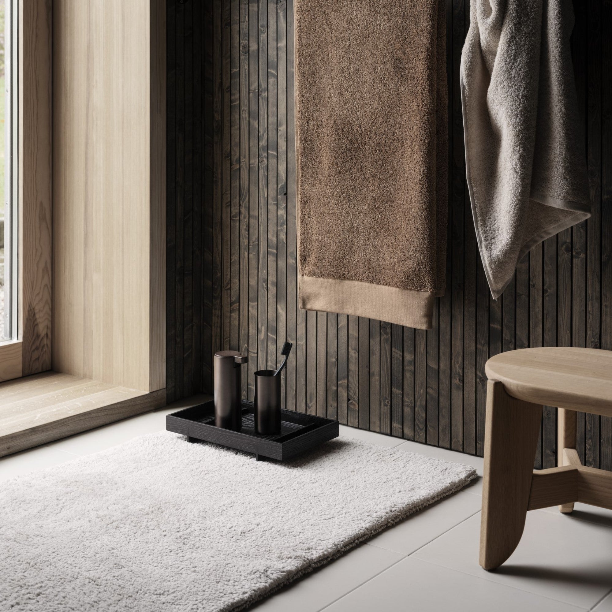 Bathroom setting with RIVA Towels hanging on hooks against wall.