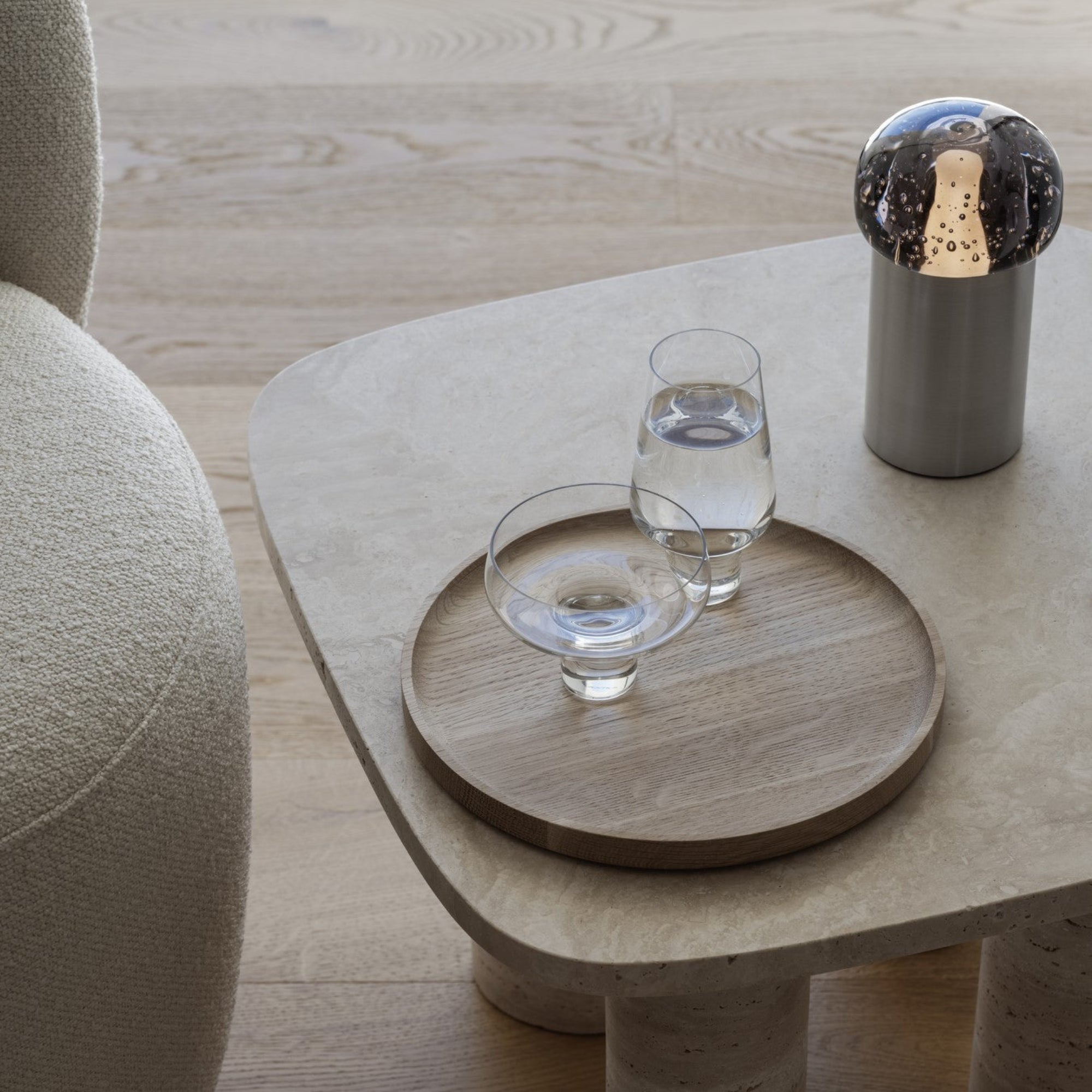 Sitting area with side table holding water glasses and modern artistic IRIS LED lamp from blomus