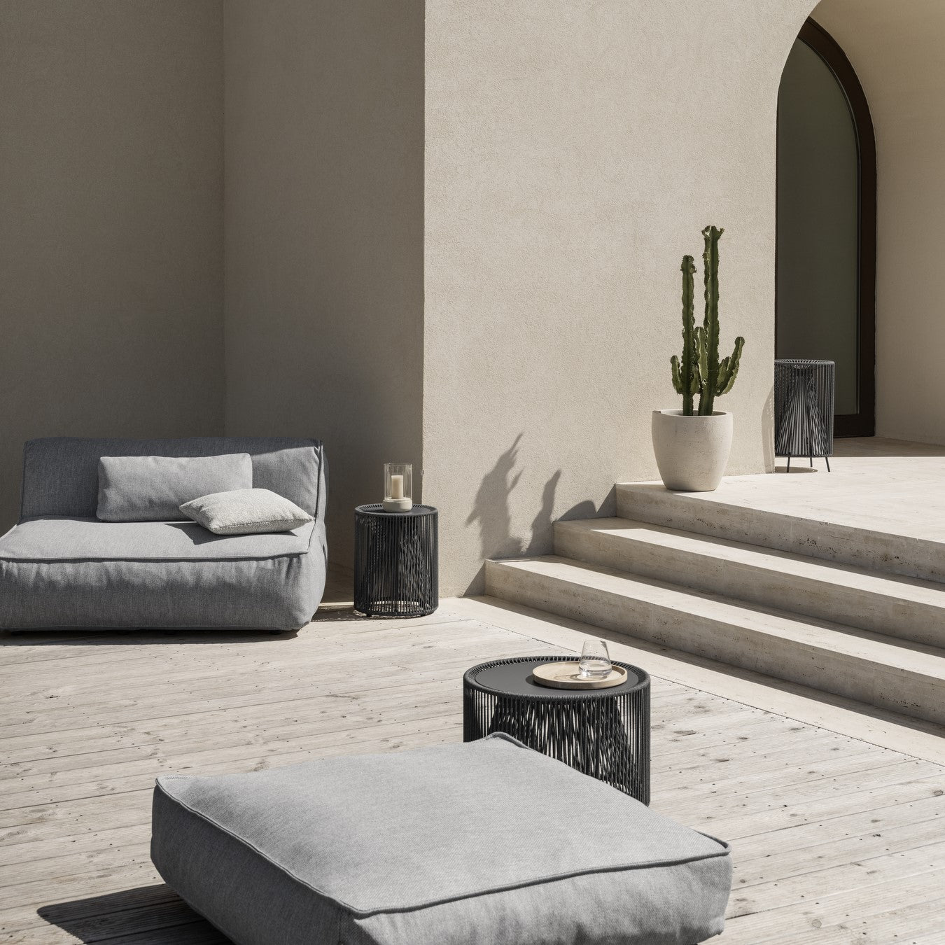 Posh outdoor lounge area with potted cactus and outdoor side able with rope sides