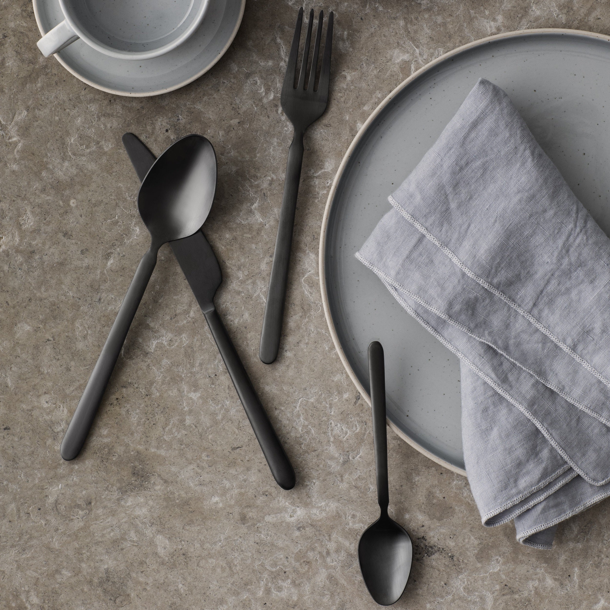 blomus STELLA black cutlery in an elegant table setting with plate on marble table