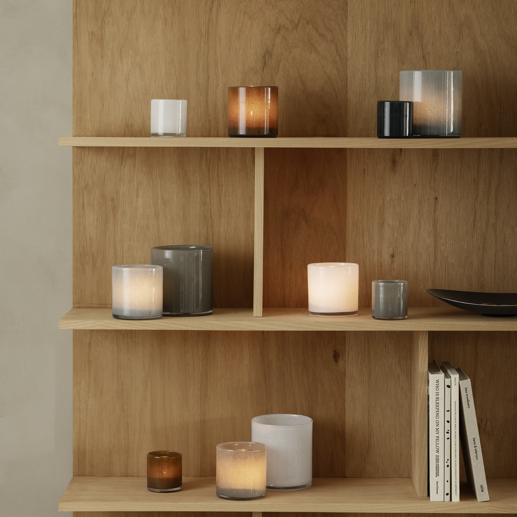 Simple Scandinavian inspired shelves displaying multiple colors and sizes of SAGA glass hurricane lamps by blomus