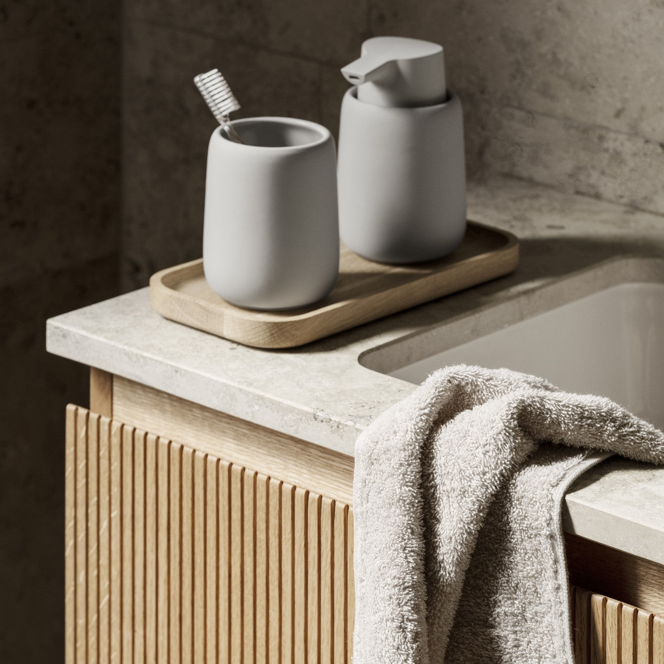 blomus OKU small oak tray in natural finish supporting bathroom accessories by a sleek contemporary sink
