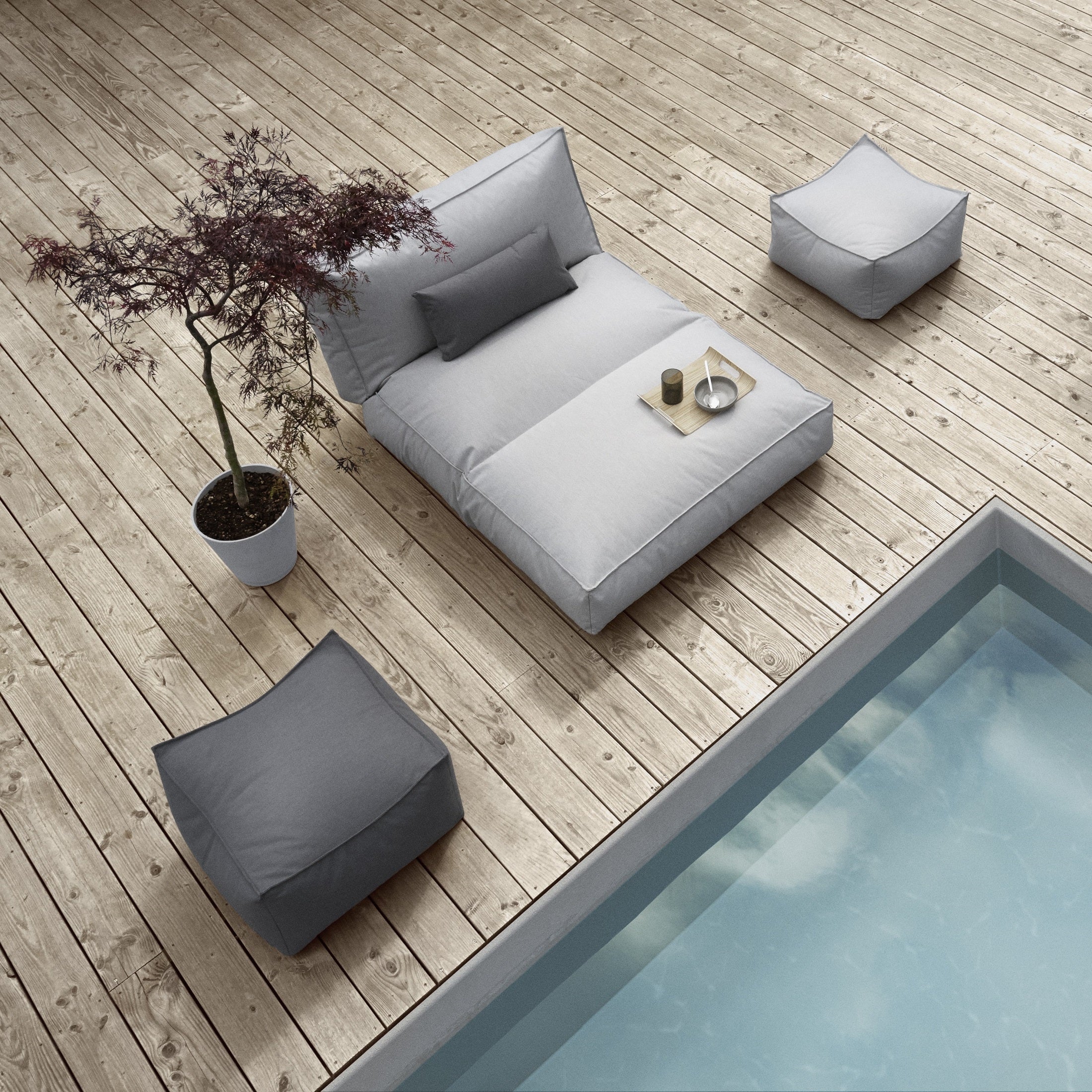 Outdoor lounger and ottomans next to a pool on a wooden deck