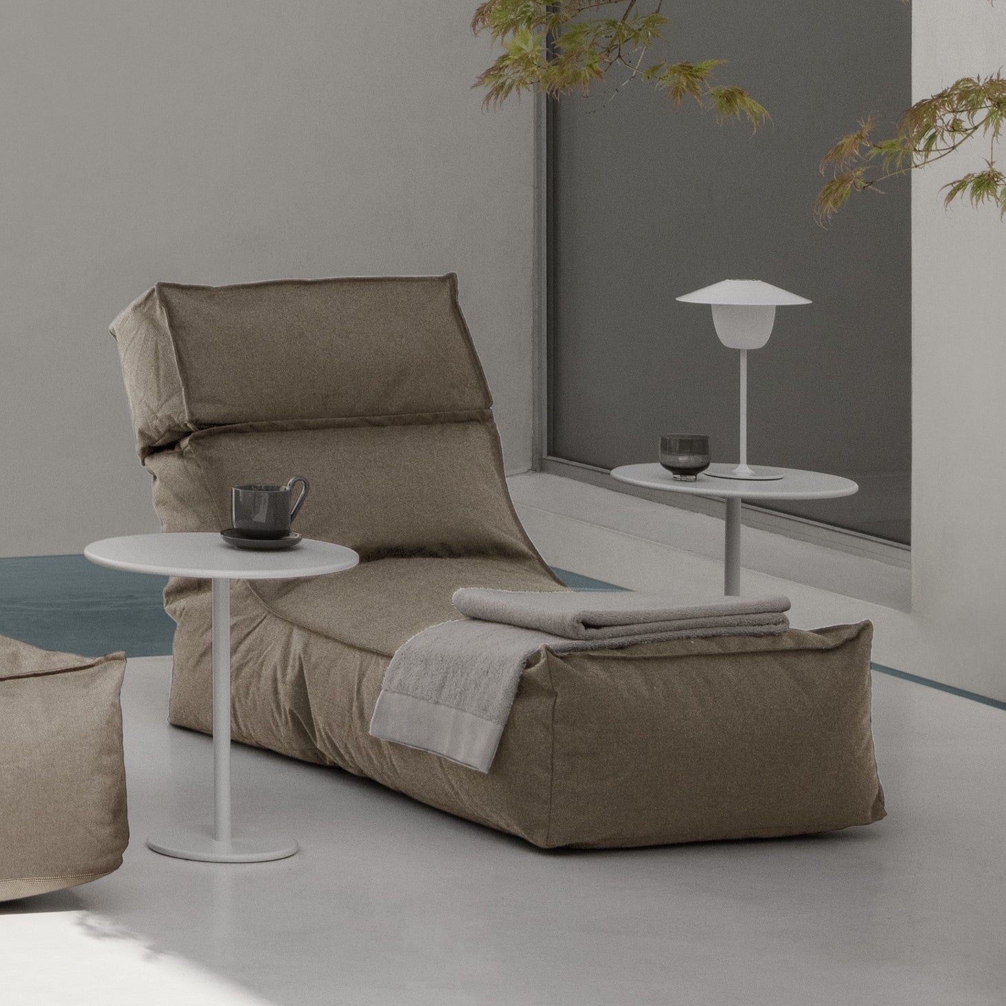 Shaded outdoor area with cozy patio lounger and side tables under a Japanese maple tree