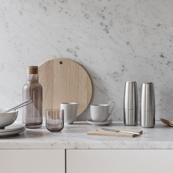 brushed stainless steel salt and pepper grinders from blomus SALPI collection alongside dishes on marble counter