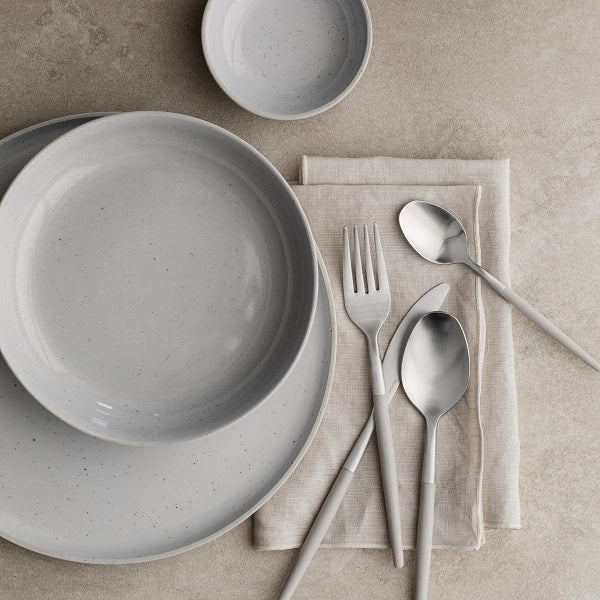 modern dining table arranged with blomus SABLO stoneware and MAXIME cutlery on a natural stone surface