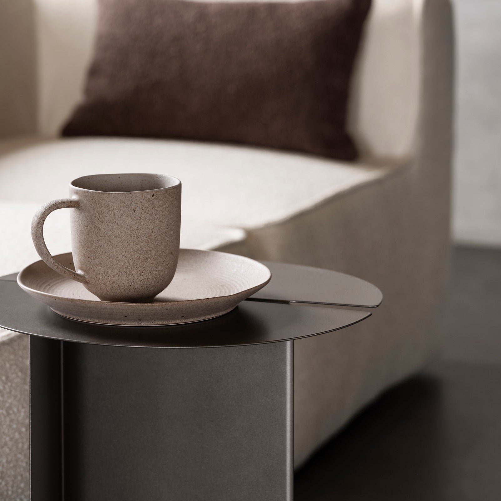 coffee cup and saucer sitting atop a modern ORU side table by blomus