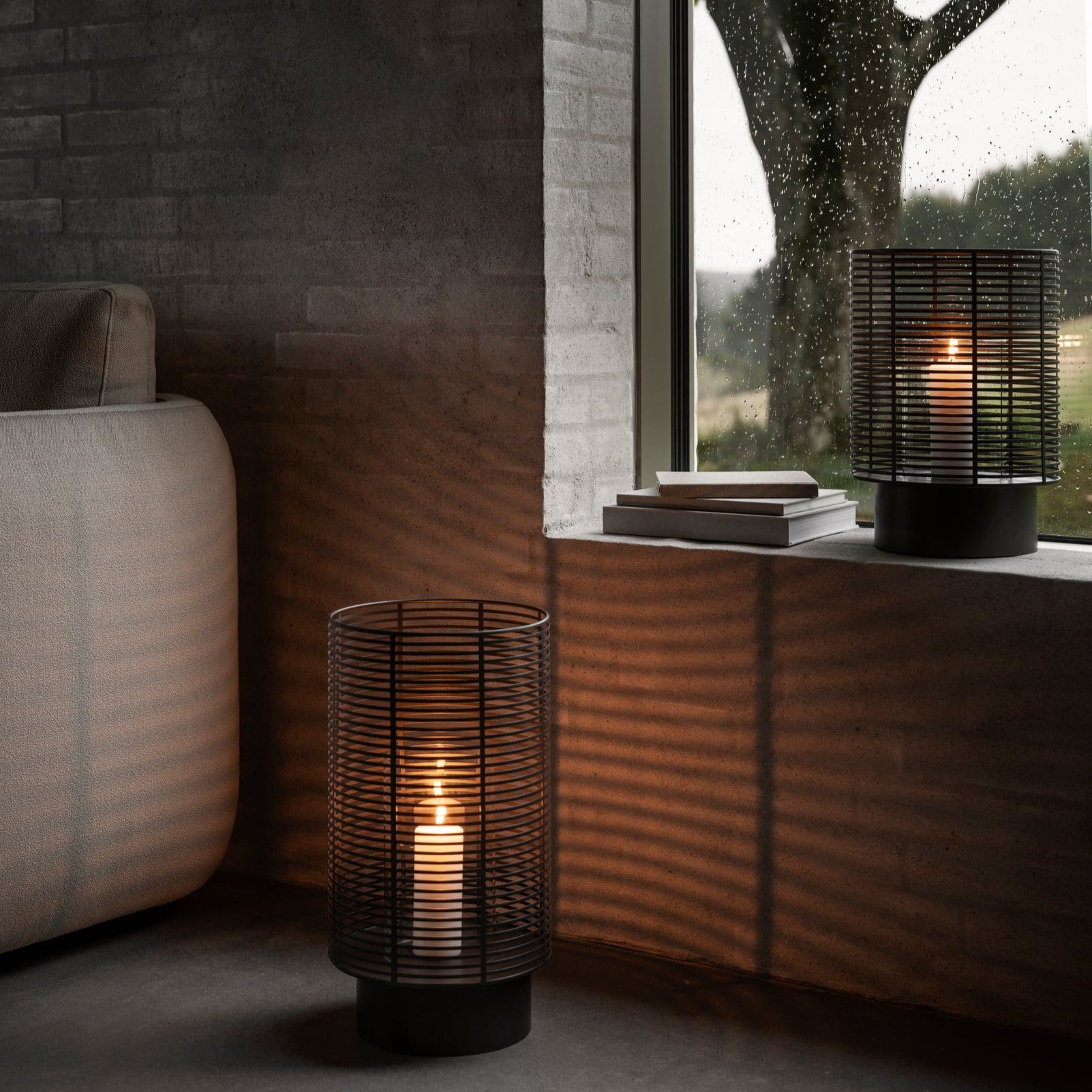 Cozy brick seating area with candles burning in metal wire lanterns casting shadows on the wall