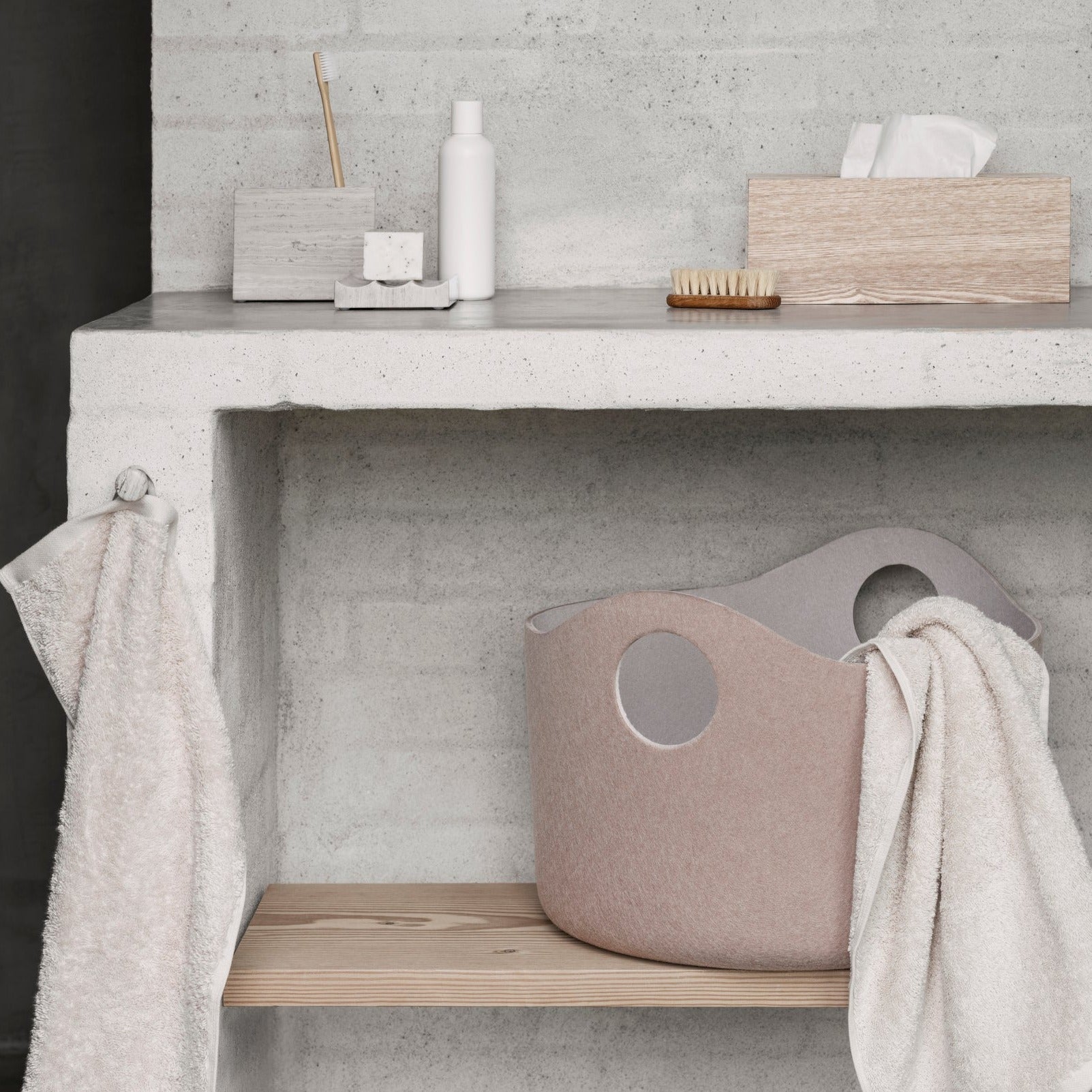 Rustic bathroom setting with toiletries and a wooden tissue box cover on brick shelf