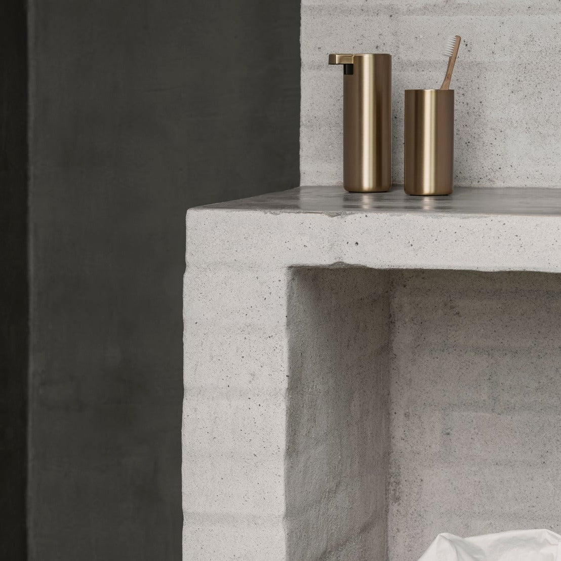 brushed finish brass tumbler and soap dispenser on a white brick countertop