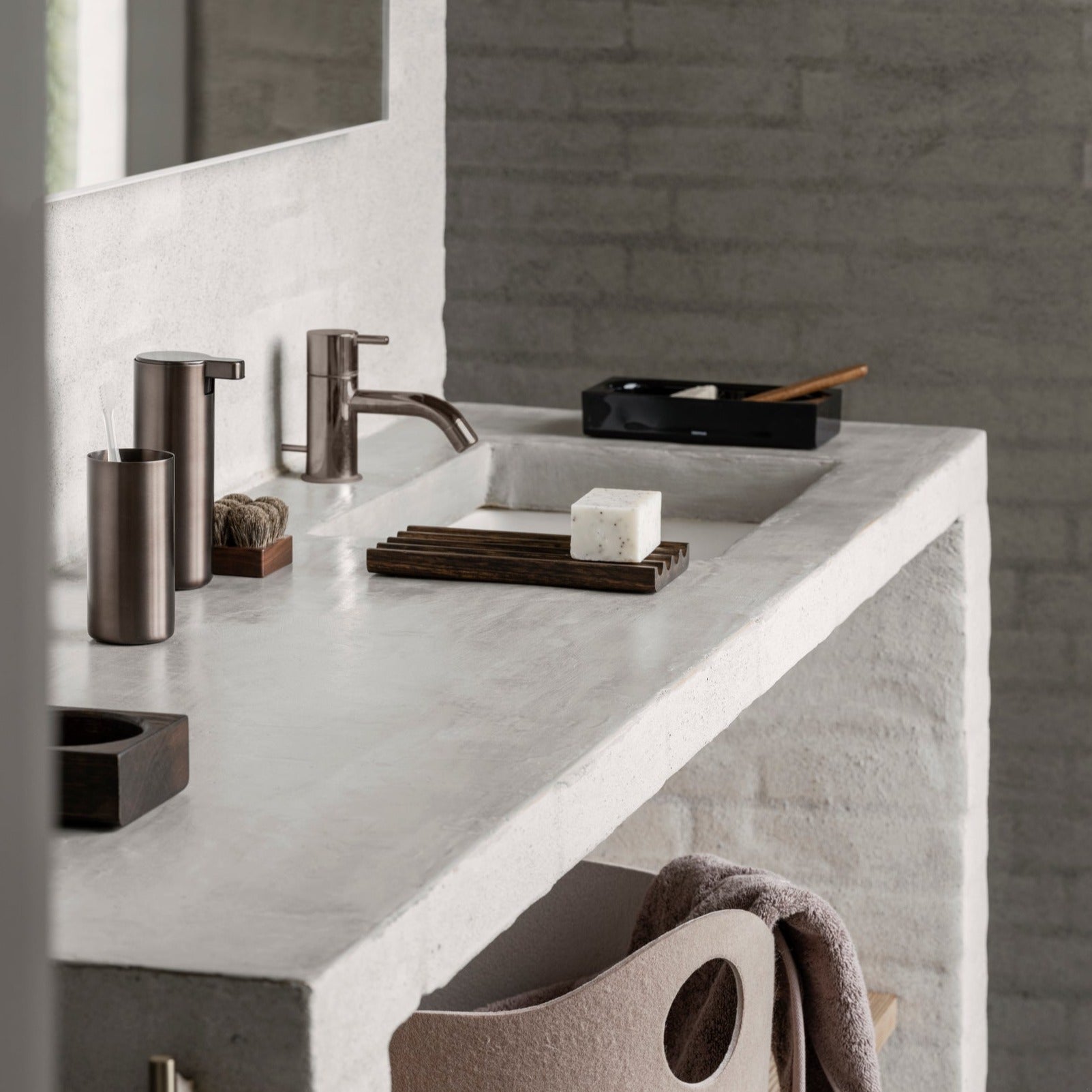 brushed metal soap dispenser and toothbrush cup in a minimalist bathroom setting
