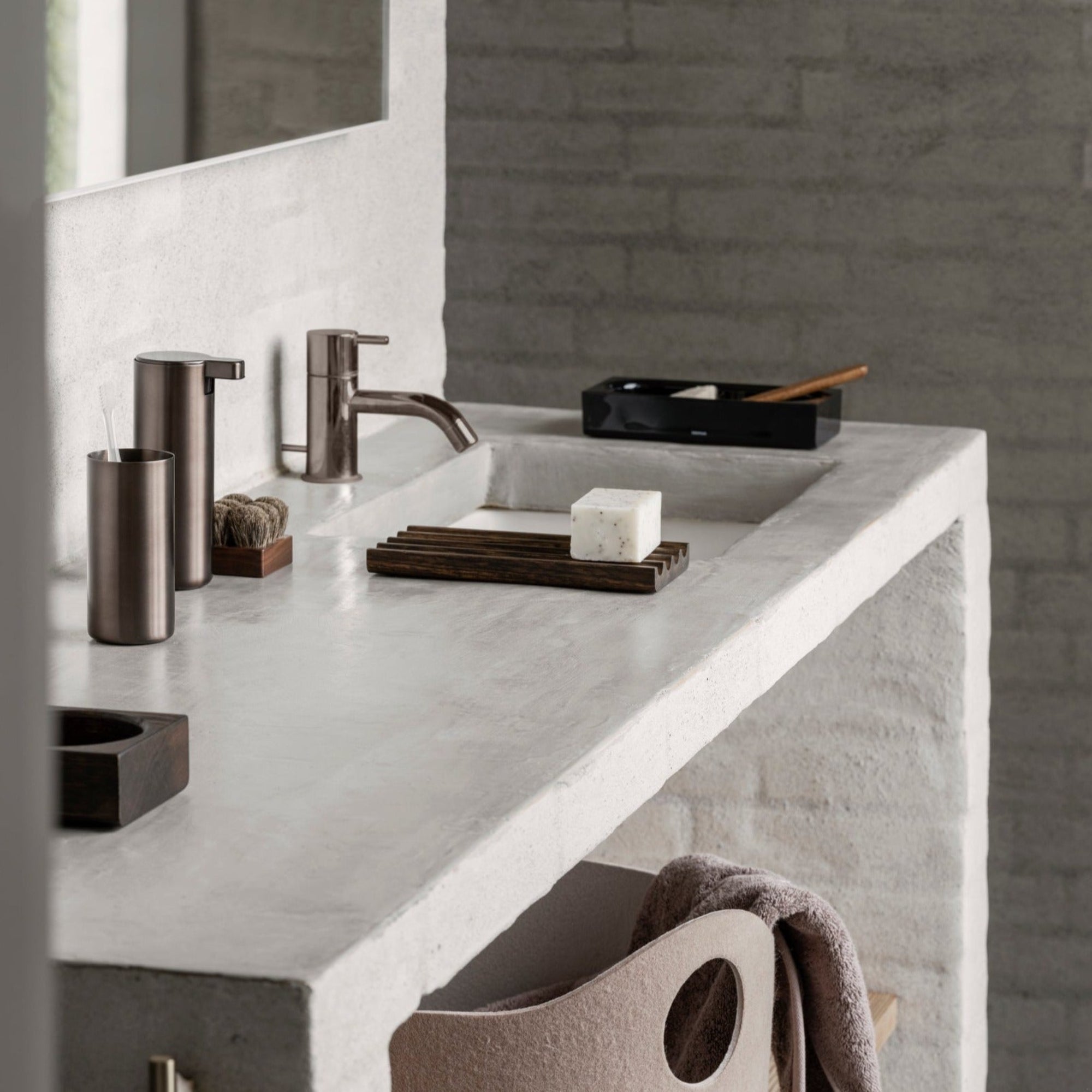 brushed metal soap dispenser and toothbrush cup in a minimalist bathroom setting