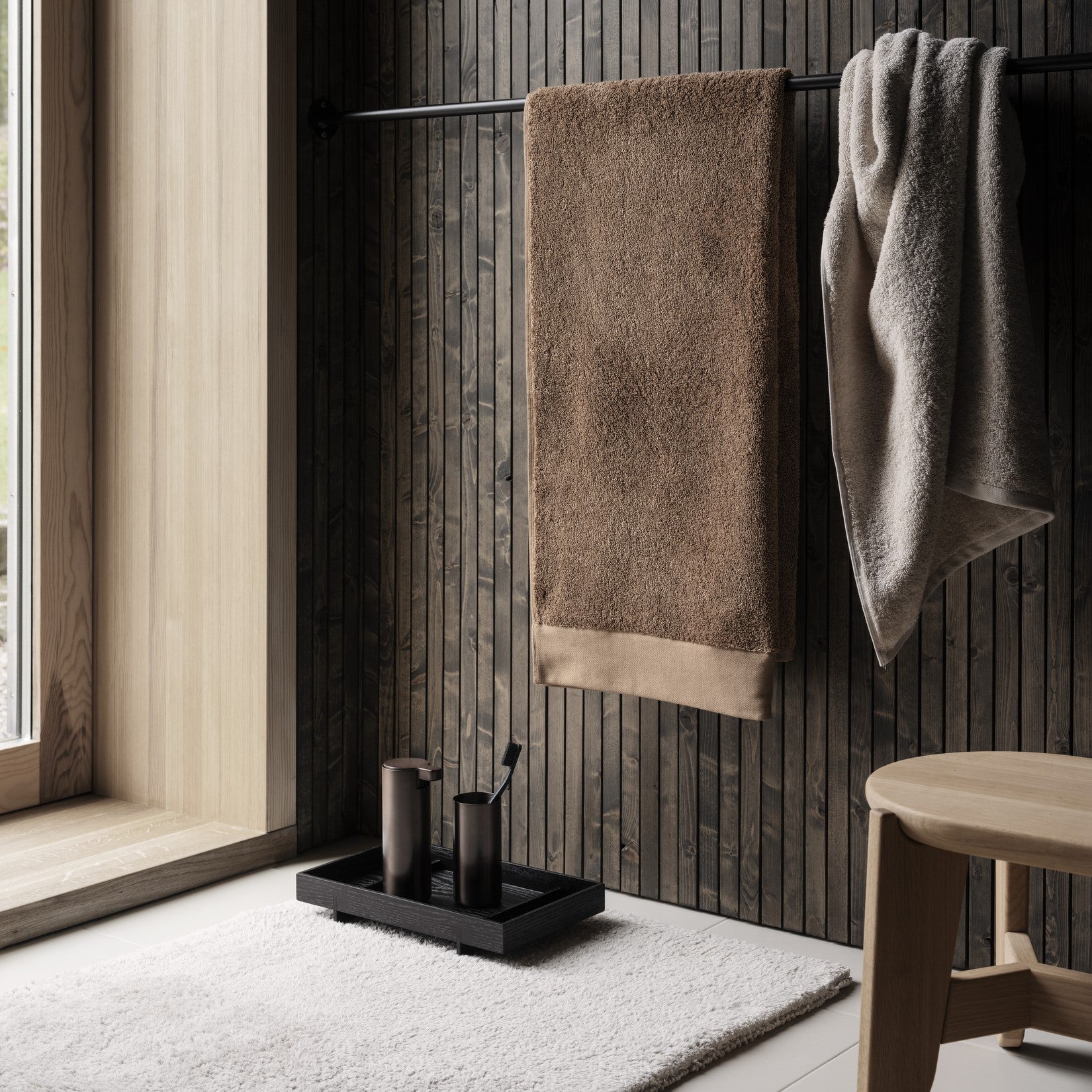 elegant bathroom setting with black oak ABENTO tray holding tumbler and soap dispenser