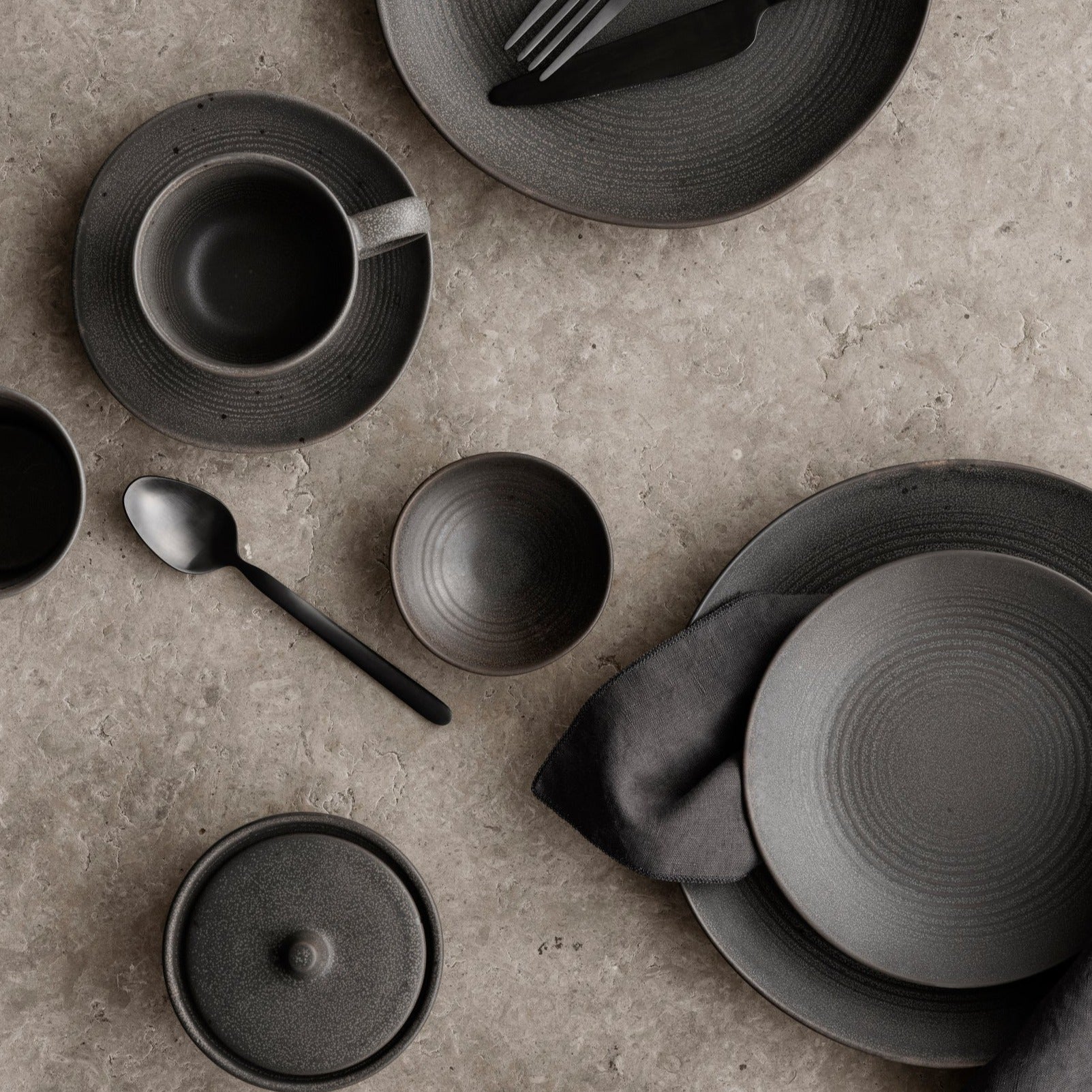 Elegant dining scene featuring blomus KUMI stoneware plates and bowls in Espresso with matte glaze