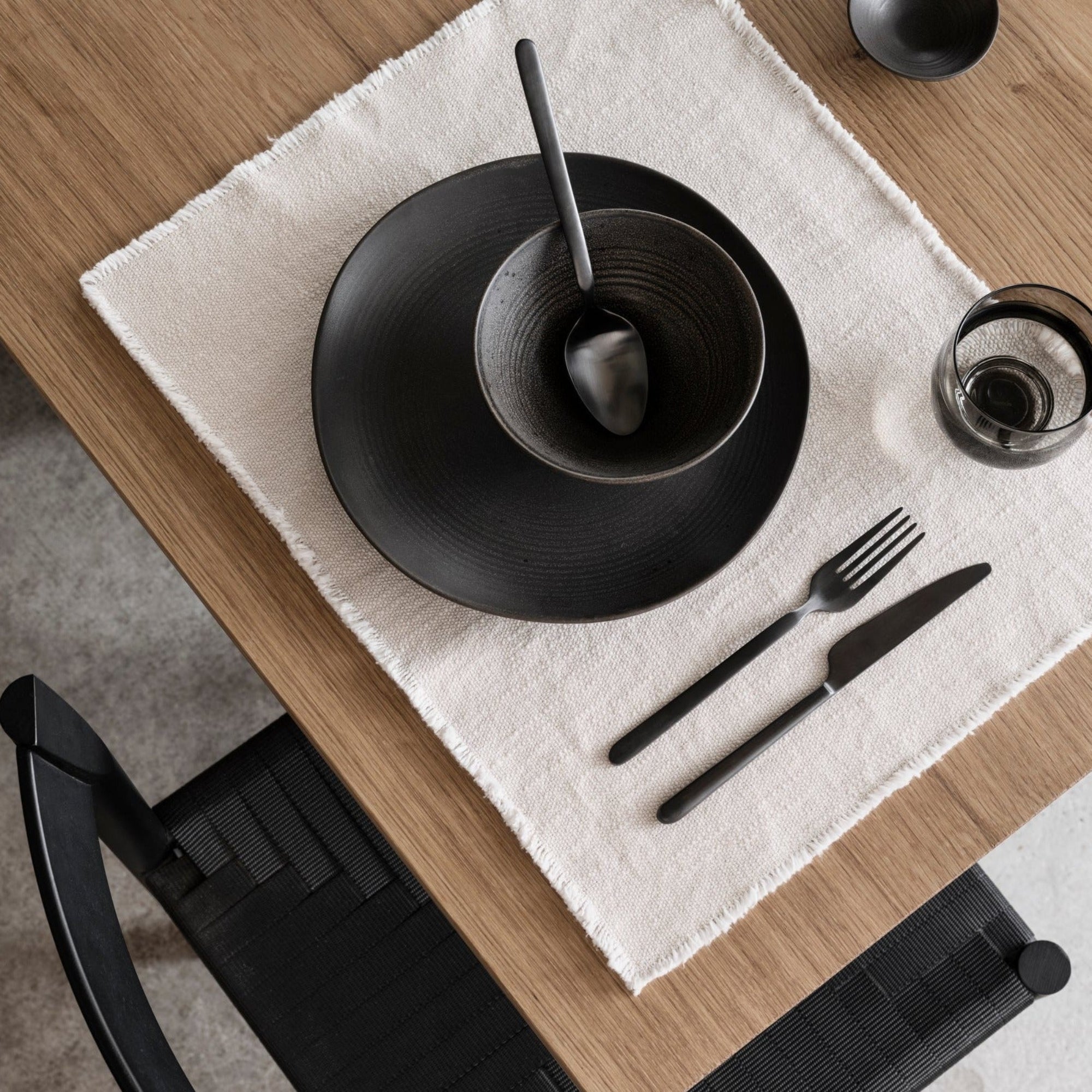 elegant black dishware set for a meal atop a white cotton placemat from blomus LINEO collection