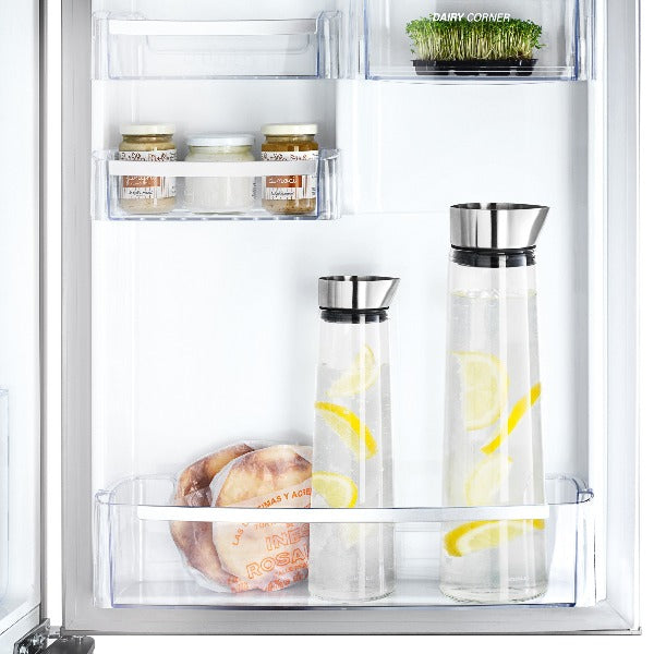 blomus ACQUA glass carafe with stainless steel lid filled with water and lemon slices in a refrigerator door