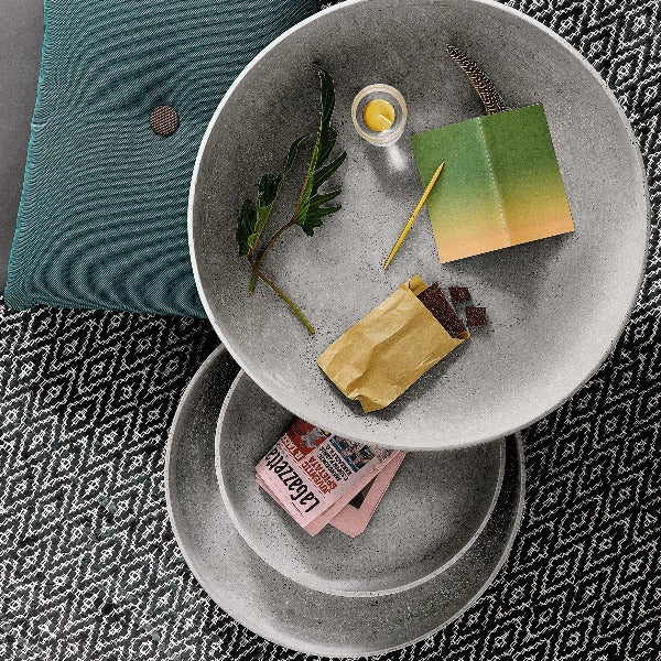 three sizes of MOON concrete bowls by blomus with an assortment of household items on an argyle rug