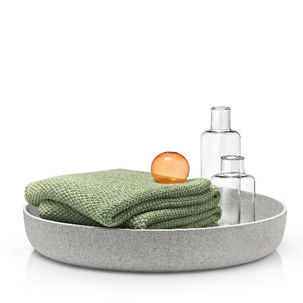 throw towels and glass bottles inside elegant concrete bowl