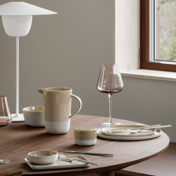 Savannah beige SABLO stoneware plates and bowls arranged in a modern lifestyle setting on wooden table