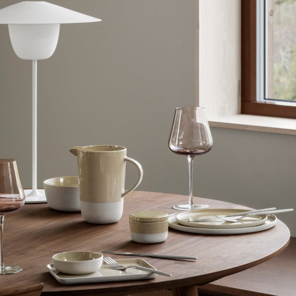 Minimalist table setting with ceramic SABLO dinnerware set by blomus with natural light and reflections from a nearby window
