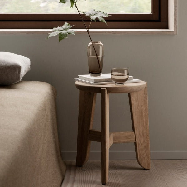 vase and water glass on top of blomus ELI stool made of solid natural oak in a bedroom