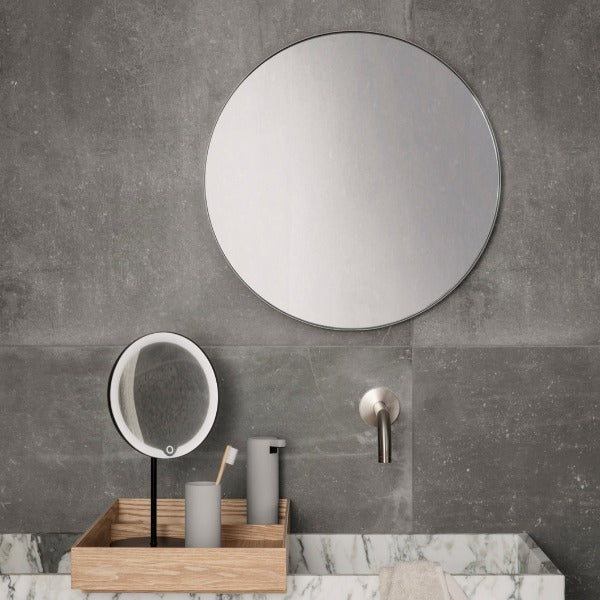 Modern LED vanity mirror displayed in an industrial modern bathroom setting with concrete walls and marble sink