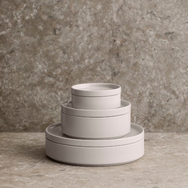 Minimalist stackable blomus PILAR Ceramic dinnerware with matte glaze bowls and plates stacked on a swirled marble countertop