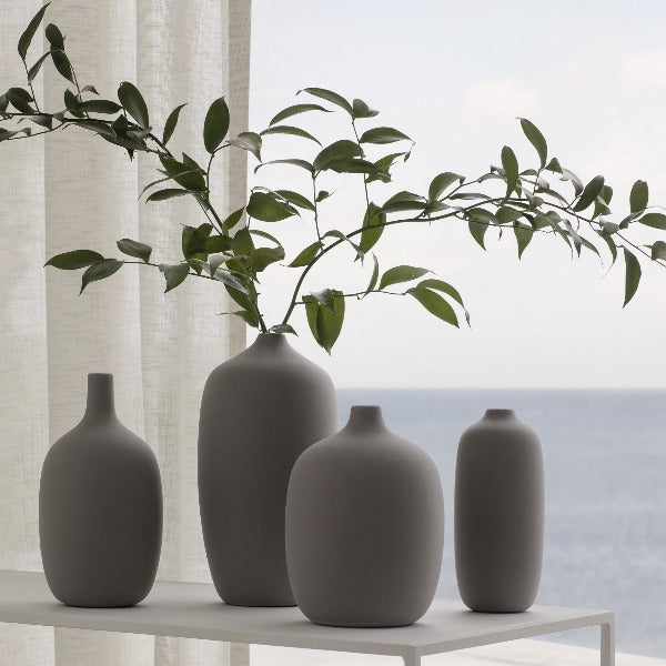 Charcoal ceramic vases by blomus with greenery in front of window with ocean view