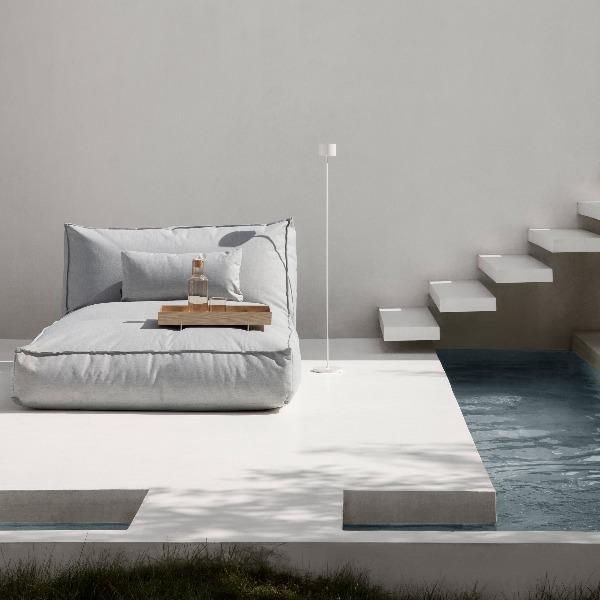 Modern pool deck with lounger and tall led floor lamp next to floating staircase