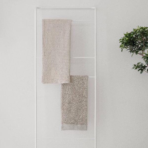 Simple white wall with Jumbo waffle bath towel draped over a towel ladder