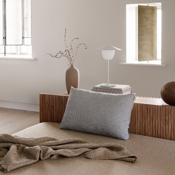 Contemporary bedroom setting with decorations and rechargeable led lamp sitting upon a stack of books