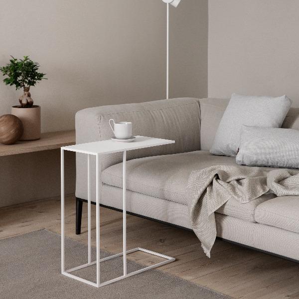 Modern sofa next to FERA side table with coffee cup on top