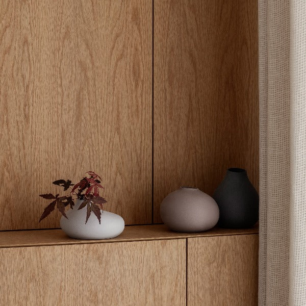 set of three decorative porcelain vases on a wooden ledge with arrangement of Japanese maple leaves