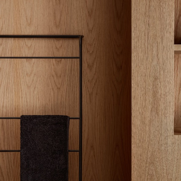 black metal towel ladder leaning against a wooden wall
