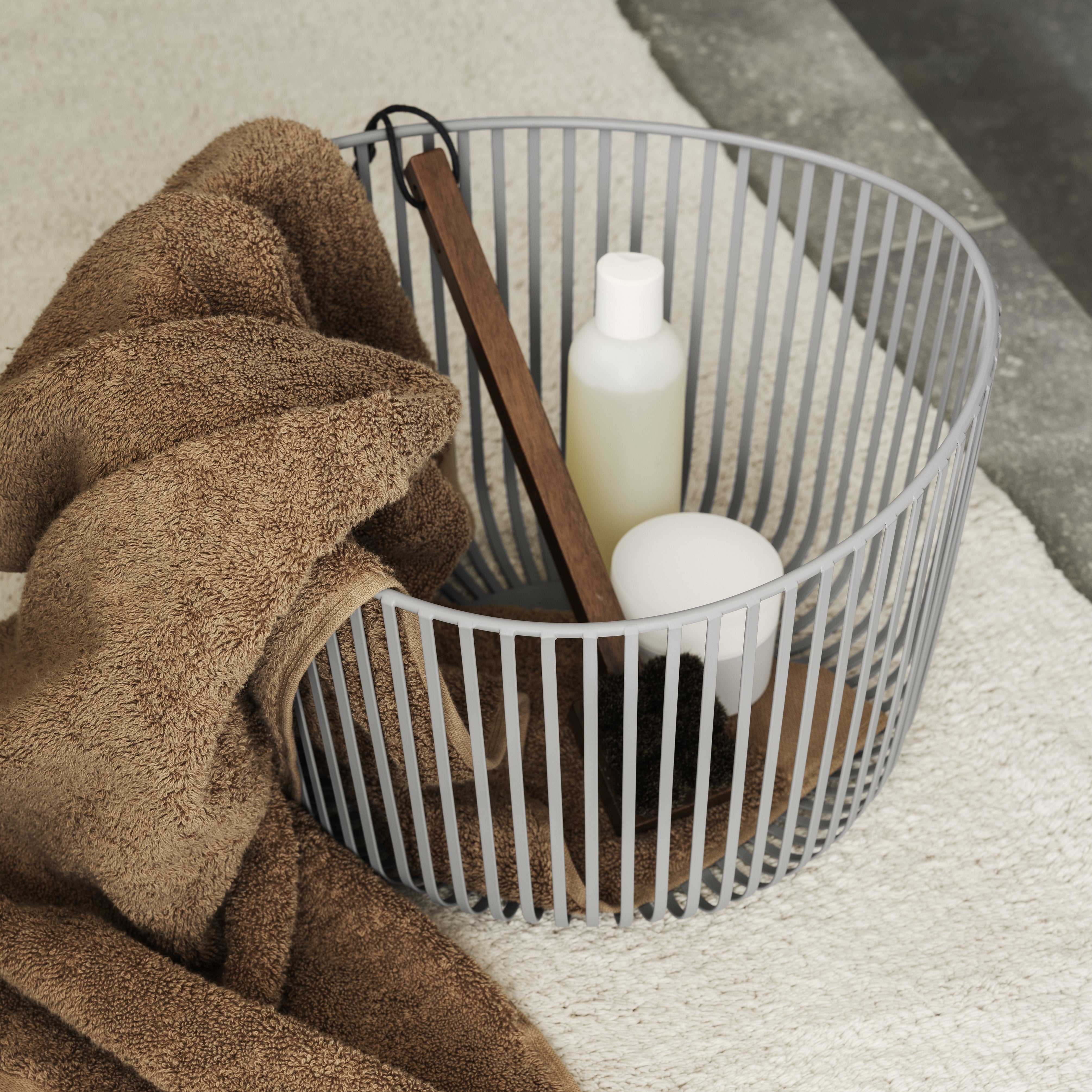 Wire storage basket with scrub brush and soap in a minimalist bathroom